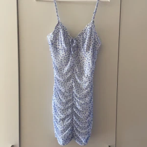 Blommig klänning - En jättefin kortare blommig klänning, tajtare modell med scrunch på sidorna, fram och bak. Endast använd en gång. Nyskick!!