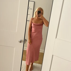 Rosa midiklänning  - Rensar garderoben och säljer nu denna fantastiska satinklänning som endast används 2 gånger.  Klänningen är från Missguided och knyts snyggt i ryggen.    Sitter som en smäck och har dragkedja i bak samt en slits på sidan.