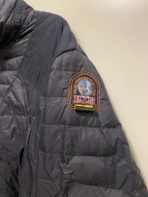 Para jumper jacka  - Dunjacka parajumper.  Storlek XXL I använt skick. Hål i rygg (lagat) och armbåge. Se sista bilden. 