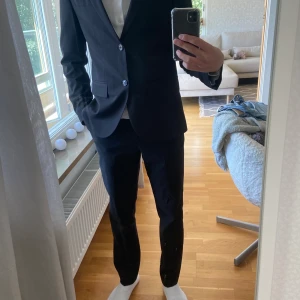 Kostym + skjorta - Jag säljer kavaj, tillhörande byxor och skjorta då de inte kommer till användning. Köptes maj 2022 och endast använda två gånger. Kavaj och byxor från HM i storlek 44 och skjorta från Selected Homme i storlek XS. Passar mig som är 182 cm och 66 kg.