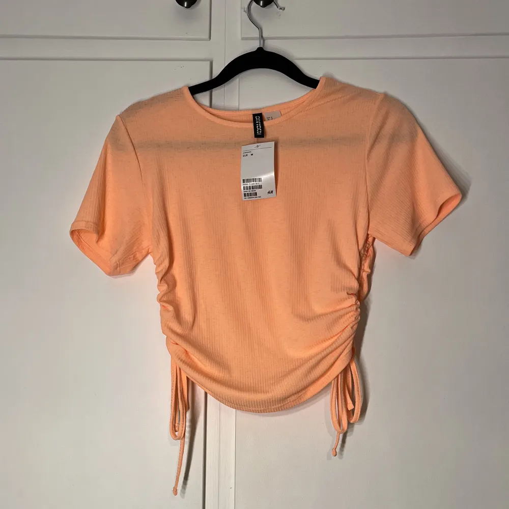 superfin neon orange ribbad t-shirt med knytning i sidorna. aldrig använd och lappen är kvar!🤩🧡✨. T-shirts.