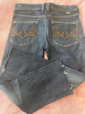 Diesel jeans strl 32 - Coola dieseljeans strl 32, avklippta ben. Innerbenslängd 115 cm. Midjemått 43 cm rakt över. Små slitningar på fickor men jag tror de var där från början. Ett pyttehål i knäveck som man bara ser om man granskar. Skickas eller hämtas i Enskede/Globen.