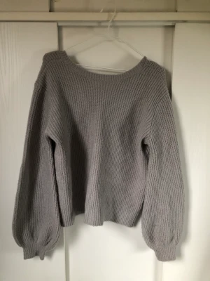 Stickad tröja - Mysig ljusgrå stickad tröja från NAKDxLinnAhlborg som tyvärr inte passar mig. Ganska stor i storleken, ”urringad” på ryggen. TAR ENDAST SWISH, FRAKT TILLKOMMER