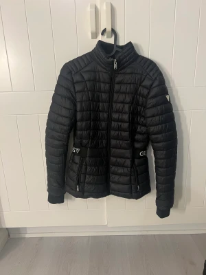 Guess jacka  - Säljer min super fina guess jacka köpt i Florida, finns inte i Sverige.  En defekt på vänstersida rygg men syns knappt. Köptes i vintras förra året använd några gånger, midjeformad. Storlek xs  Nypris 10.000 Säljer för 2300 pga av defkten på ryggen 