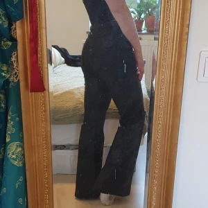Hella Retro Flared High Waist - Coola utsvängda jeans. Svarta med en lätt läderish finish på dem. Oanvända och lapparna sitter fortfarande kvar  Storlek: M/30