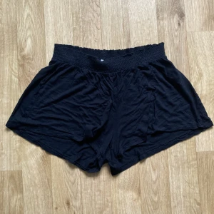 Svarta shorts - Svarta shorts i 100% viskos fint skick. Säljs då de är för små för mig. Midja: 34cm (stretchat till 42cm), längd ytterben inklusive midjeband: 29cm.