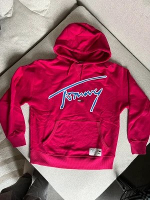 Tommy jeans hoodie - Rosa hoodie från Tommy jeans, säljs inte längre, nypris ca 1100kr, tjockare tyngre material så riktigt skön hoodie. Använts hemma ca 5 gånger. Sitter oversized på mig (brukar ha S ibland m)