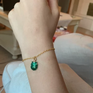 Armband med snäcka - Armbandet är ca 15 cm och snäckan är ungefär 1 cm. Armbandet är nytillverkad och handgjort. Den är ej av guld. Snäckan är grön med glitter i och är guldig på baksidan 