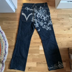 DLX JEANS - Ascoola jeans från Deeluxe Wear med silvrigt broderi-tryck på. Även dessa är köpta på second hand men har inga större defekter. Inga fläckar eller hål. Lite nertrampat längst ner på jeanskanten dock. Står ingen storlek men gissar 32/32 (är 180 cm lång)
