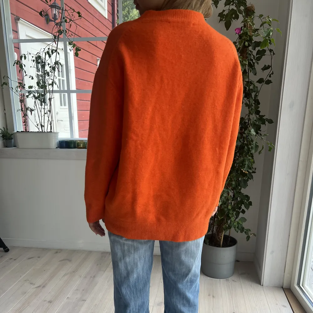 Somrig orange stickad tröja. Tecken på användning finns men inga större slitningar.. Stickat.