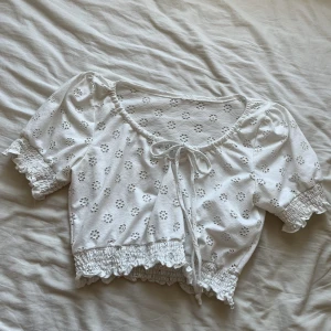 Vit topp - En jättesöt vit topp med blommor i tyget och snörning i fram.