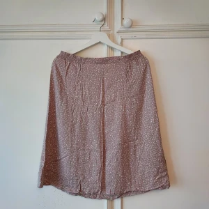 Kjol - Beige kjol med vita och rosa blommor ifrån Westerling. St 38 men passar även 40-42. Justerbar midja