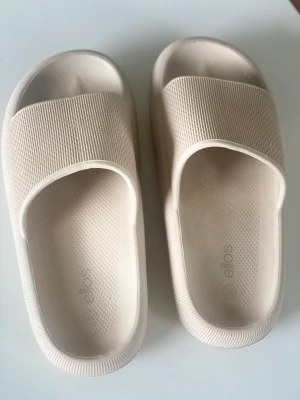 Tofflor  - Beiga tofflor från Ellos.  Använda 1 gång. Nypris ca 270kr