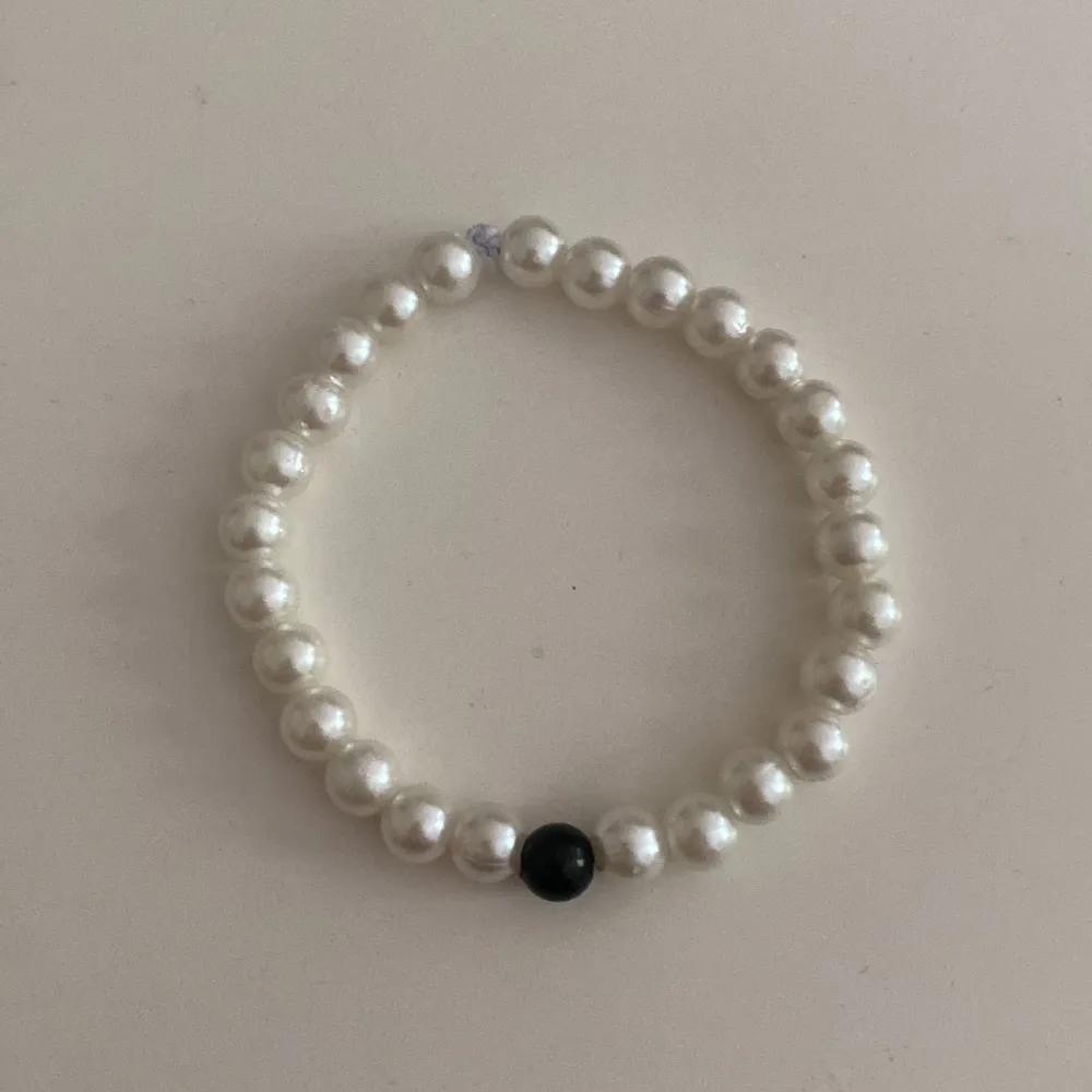 Enkelt armband med trendiga vita pärlor och en svart pärla i mitten❤️. Accessoarer.