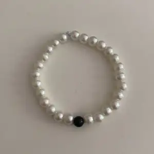 Enkelt armband med trendiga vita pärlor och en svart pärla i mitten❤️