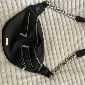 Magväska Ivy Revel - Magväska från Ivyrevel. En stor ficka och två små. Går att justera längden på den. Använd några gånger, superfint skick  Bredd: 25 cm  Höjd: 17 cm 