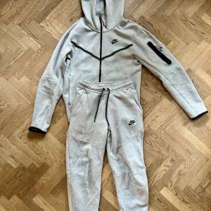 Set: Grå Nike tech fleece strl XS (byxa och tröja) - Köpt i våras på JD. Tröjan är så gott som ny (inget slitage el nopprig). Byxan är också fin men har tyvärr ett hål. (Skriv för tydligare bild). Setet är använt fåtal gånger.  Nypris 2300. Mitt pris 950 + frakt (kan diskuteras) 