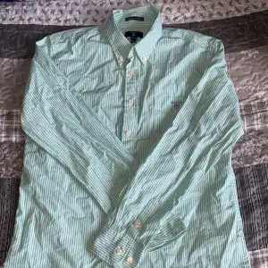 Denna skjortan är i bra skick och är använd fåtal gånger jag säljer denna skjortan eftersom att den är för liten för mig. Skjortan är randig med ljusgröna och vita smala ränder storleken är 158-164 centimeter och 13-14 år