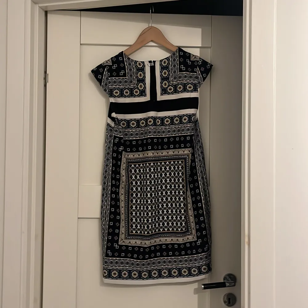 Luftig klänning från mango. Klänningen är vit med ett blå, gul, svart orientaliskt mönster. Klänningen slutar vid låren och ser helt otrolig ut både utomlands men också här hemma i Sverige 🩷🩷. Klänningar.