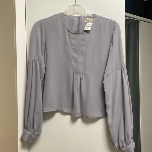 Shifonn blus -ganska transparent - ”Transparent” shiffon blus i färgen grå från märket Abaci. Helt ny i skick. 