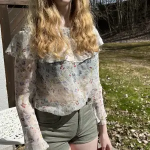 En blommig mesh tröja som passar perfekt till sommarens varma väder. Offshoulder modell men går även att ha över axlarna. 