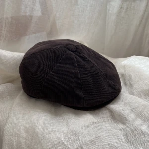 Brun gubbkeps i corduroy  - Fin brun gubbkeps i corduroy. I fint skick, hel!  Har en knapp i fram så man kan justera hur man vill att skärmen ska vara.