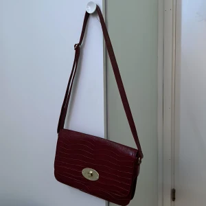 Röd handväska  - Säljer den här vintage vinröda handväskan/ axelväska som är i väldigt bra skick 