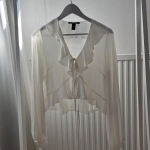 Vit sommarblus  - Supergullig blus med volangdetaljer. Går att ha både knuten eller öppen.