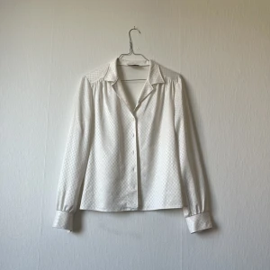 Blus - Vit blus med glansigt rutigt mönster. Passar 36-40 / small, medium, large beroende på hur man vill att den ska sitta! 