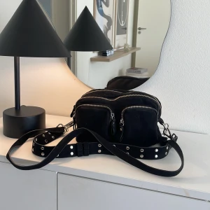 Svart liten Väska  - Säljer denna väska från GinaTricot då den inte längre används. Fläckar i ena facket, dock inte provat att tvätta bort därav pris Om de önskas kan jag testa att köra den i tvättmaskinen!