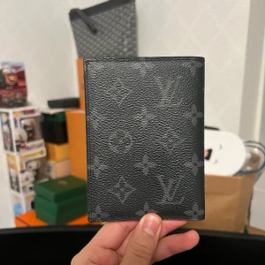 Louis Vuitton Eclipse Monogram Passhållare - Bra skick men använd och finns spår av användning runt kanterna. 