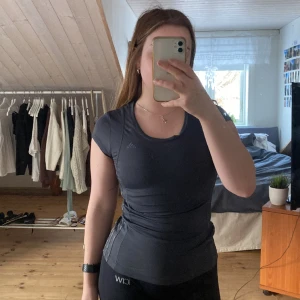 Adidas träningstop - Mörk grå tränings topp från adidas. Stretchig och formar jätte fint, kommer tyvärr inte till användning.  Storleks lappen är bortklippt men skulle uppskatta att den passar xs-s💕 