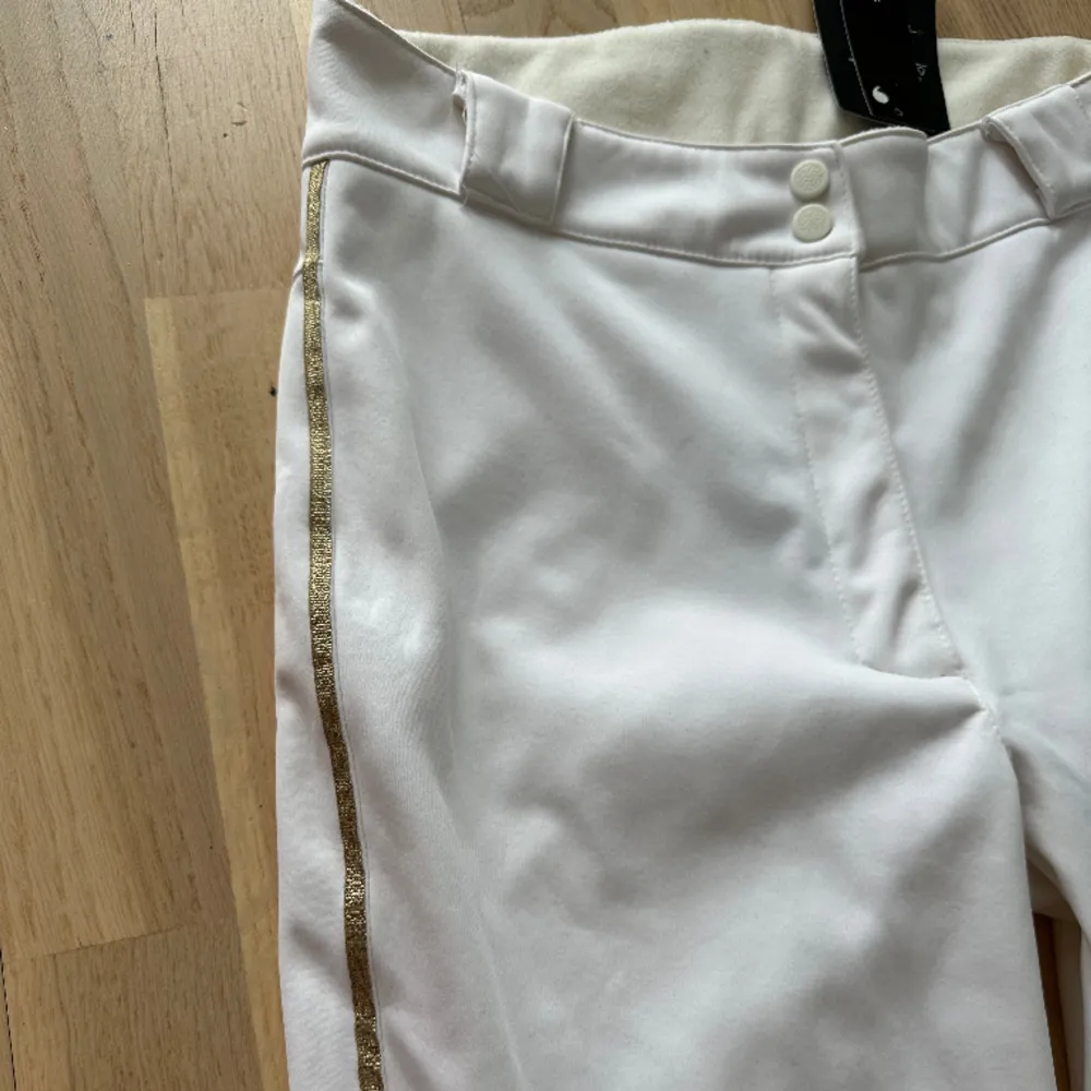 Vita utsvängda skidbyxor som är oanvända med prislappen kvar. Byxorna har gulddetaljer på sidorna (se bild). Jeans & Byxor.