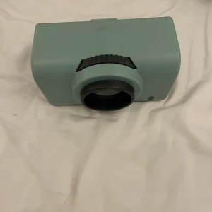 Projektor - Läs bio! Liten projektor man kan lägga mobilen i så spelar den upp det när man sätter själva ”linsen” eller hur man ska säga mot en vägg i ett mörkt rum. Perfekt hemma bio om man inte har en stor tv/projektor💓Köparen står för frakten!💕