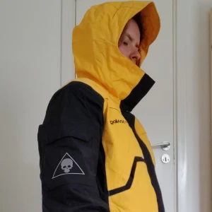 Analog Mandalore alpinjacka M Unisex - Skid/snowboardskaljacka i väldigt gott skick som använts sparsamt. 6 ytterfickor varav 1 på vardera arm, 1 inner vatten/fuktavvisande gogglepocket för skipass och lång ficka på ena sidan för hörlurar så du slipper allt trassel. Ventilation under armar. 