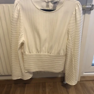 Blus  - Off white blus som är väldigt vacker på. Den framhäver byst och ger en fin midja.  Knäppes backtill i nacken m en knapp.  Medium storlek cirka 