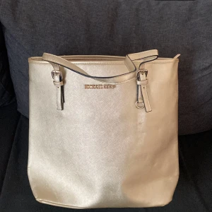 Micheal kors väska  - En stor guldig micheal kors väska. Ej använts. Får plats med mycket 