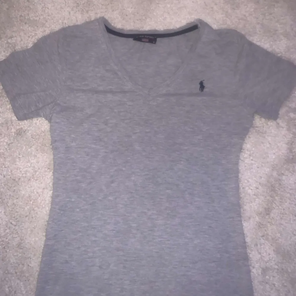 Säljer denna gråa V ringade  Ralph Lauren t-shirten som inte kommer till användning längre. Inga defekter och är i storlek S men passar även som xs!!🥰 . T-shirts.