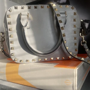 Valentino garavani väska 🤍🧡🩵 - Hej! Säljer denna superfina valentino garvani rockstud väska i ljusblå/ ljusgrå med guld detaljer då den inte längre kommer till samma användning🧡, väska är i gott sick och rymmer mycket . Väskan har både handtag och axelrem. Dustbag medkommer! 🤍🧡🩵