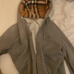Burberry zip hoodie - Grå Burberry hoodie storlek M. Använd ett par gånger men inga fläckar och utmärkt sick. Helt äkta som även kan bevisas tillskillnad från många andra här! 