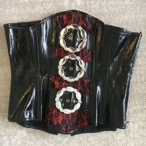Korsett  - Snygg gothisk korsett som inte kommer till användning. Snörning baktill och stora dekorativa spännen