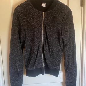 Glitter tröja - Svart glitter tröja med dragkedja. Använd vid ett tillfälle. Köpt på Vero Moda i storlek S.