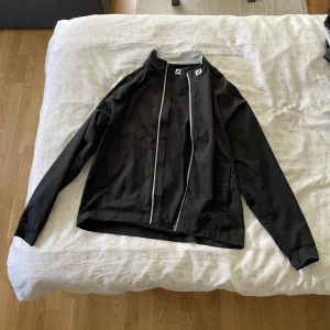 Footjoy Vindjacka - Säljer nu min vindjacka i storleken M som endast har använts ett fåtal gånger. Jag är 188 cm lång och väger ca 86 kg och den passa mig perfekt. Priset är inte hugget i sten!  