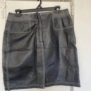 Skinkjol med vita sömmar  - En fin och unik skinnkjol med vita sömmar. Jättefin men tyvärr för stor för mig därav är den aldrig använd.