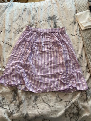 Kjol  - En lila och vit randig kjol, kan stryka den innan köp, kostar 35kr+20kr frakt 