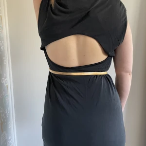 Klänning med öppen rygg & slits strl L - Oanvänd suuuper mjuk och följsam klänning med öppen rygg och slits på sidan. Gråsvart. Obs! Bältet ingår ej.