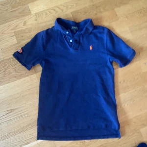 Ralph Lauren piké  - Den är väldigt bra skick barn L (14-16) men passar också herr xs den är en piké som är köpt på us Open väldigt stor tennis Tunering inte många gjordes av denna och den är väldigt svår att få tag på👍 skriv vid minsta fråga 