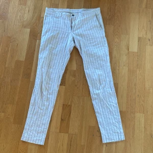Linnebyxor  - Jättesköna linnebyxor i beige färg med lätt blåa ränder i storleken 50. Ganska slim i passformen. 