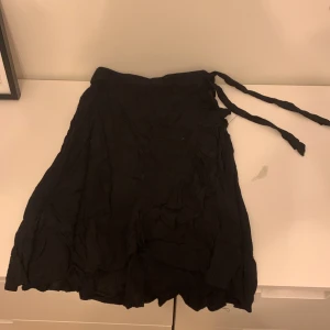Svart kjol, den är inte en kortkjol men inte heller än långkjol. Jag som är 1,53 så är den ner till precis under mina knän.  - Jättebra skick, bara används några få gånger. Jätte skönt material. Kjolen har också ett band som man kan göra en liten rosett i midjan om man vill. Kjolen har också en volang.