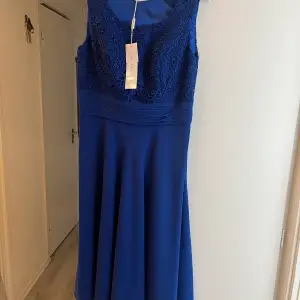 En fin blå klänning från Gina Bacconi men ett fint mönster. Helt oanvänd 
